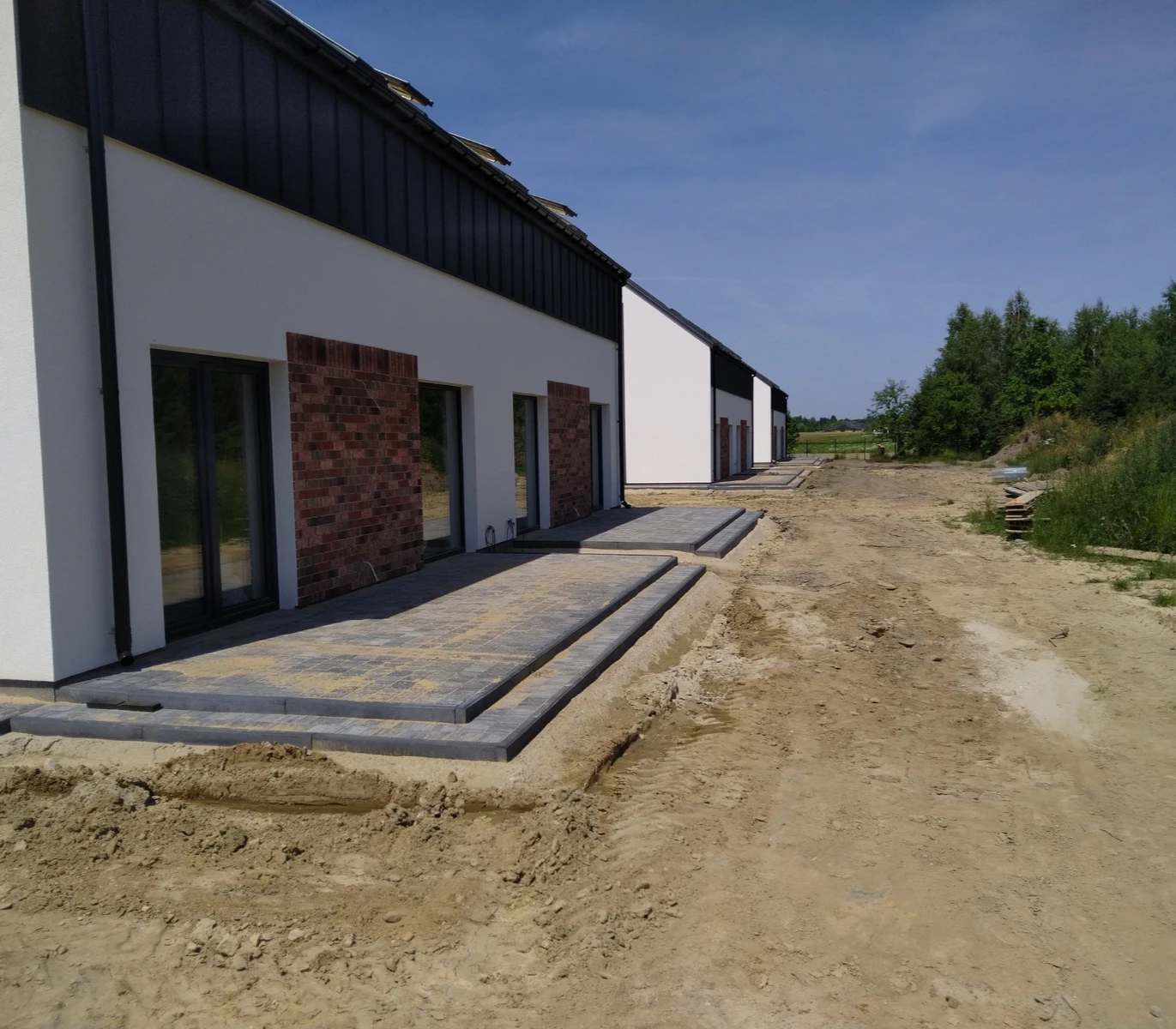 Tarasy z kostki brukowej na przygotowanym podłożu przed budynkami mieszkalnymi